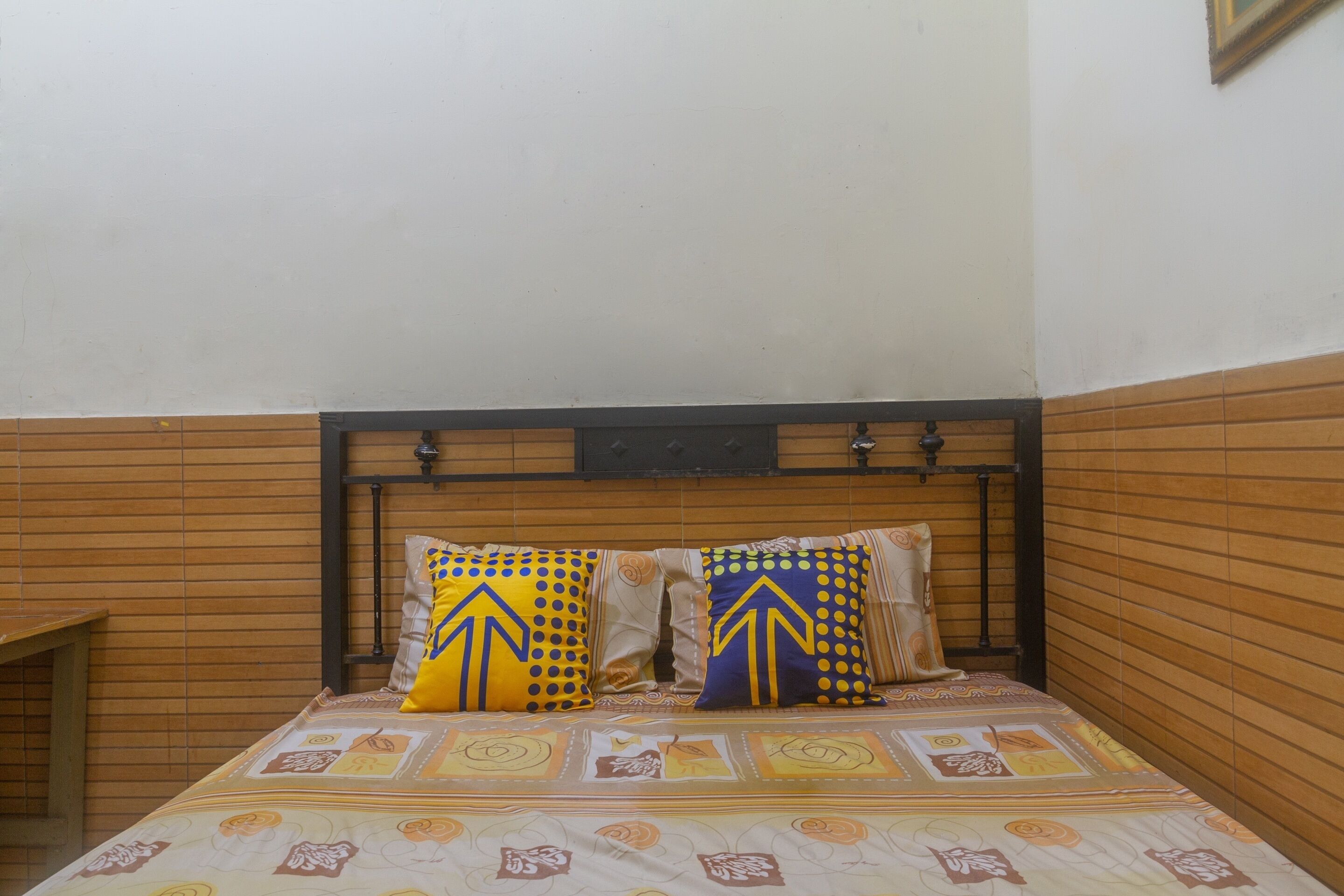 Een bed met een beddekleed met een patroon en twee kussens met pijlpuntmotieven.