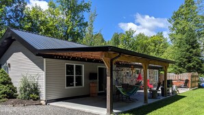 A house with a covered patio, a hammock, and a stone wall. - Chalet lacbrome (Knowlton)