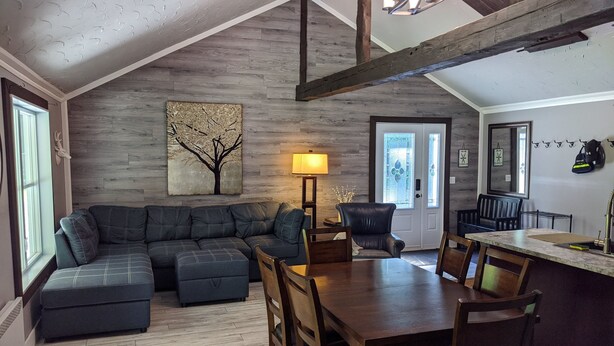 A cozy living room with a sectional sofa, a dining table with chairs, a fireplace, and a large window. - Chalet lacbrome (Knowlton)