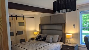 A bedroom with a bed, bedside tables, a wardrobe, and a window with a view of greenery. - Chalet lacbrome (Knowlton)