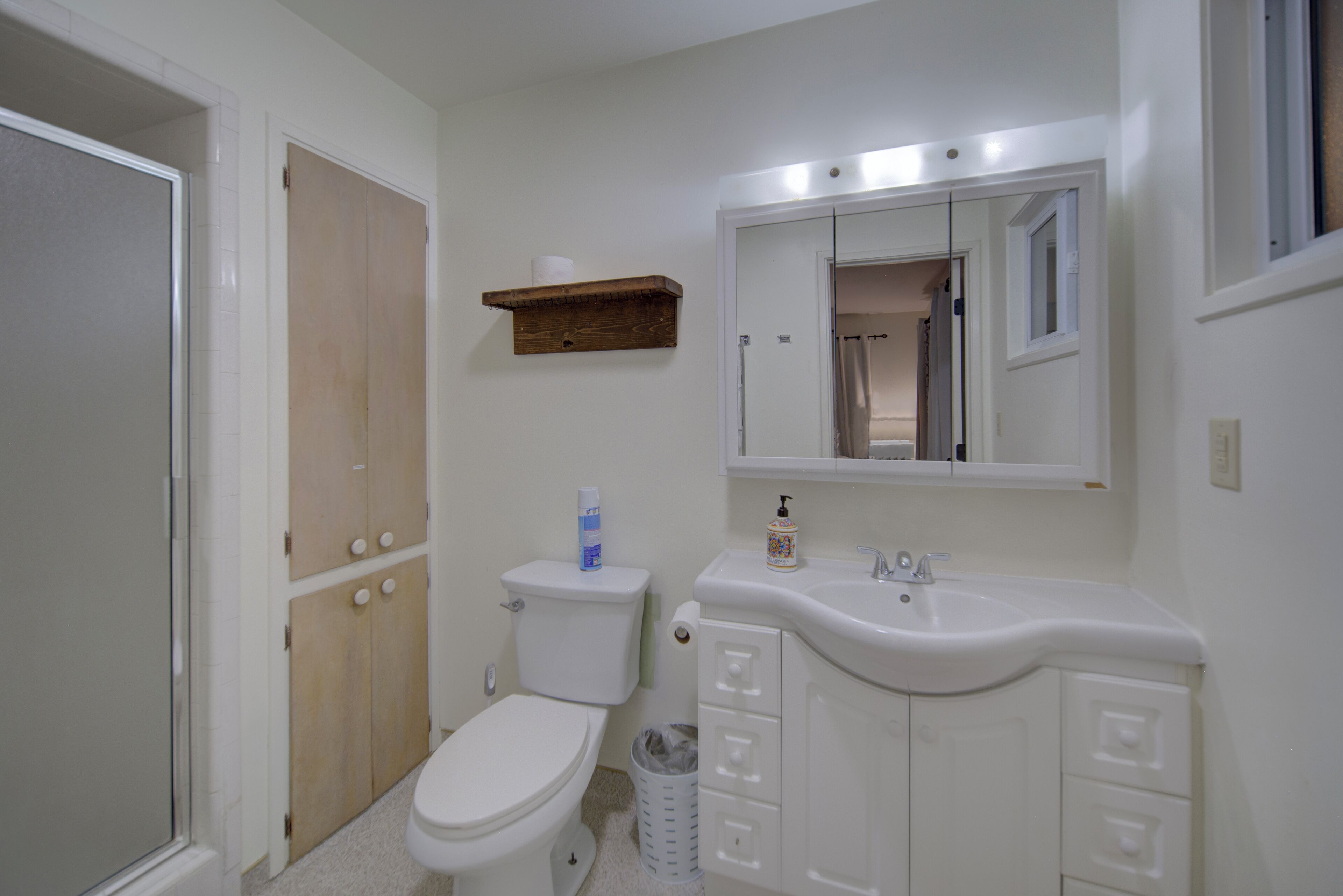 Een badkamer met toilet, wastafel, spiegel en houten kastjes.