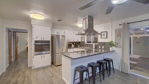 Uma cozinha moderna com ilha central, eletrodomésticos de aço inoxidável e um ventilador de teto.
