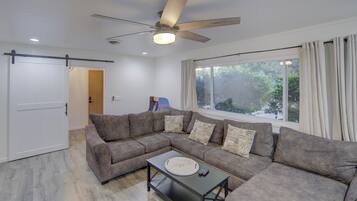 A modern living room with a sectional sofa, a coffee table, and a ceiling fan.