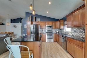 Una cocina moderna con armarios de madera, electrodomésticos de acero inoxidable y una isla central.