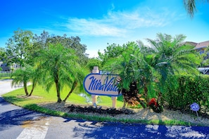 Schild für "Miravista" mit blauem Himmel und üppigem Grün im Hintergrund.