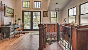 Quarto amplo com escrivaninha de madeira, uma cadeira e uma janela grande com vista para o exterior.