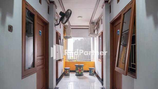 A hallway with a tiled floor, wooden doors, and a window at the end. - OYO 3892 Athaya Guesthouse Syariah (Depok)