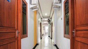 A corridor with wooden doors, white walls, and a tiled floor. - OYO 3892 Athaya Guesthouse Syariah (Depok)