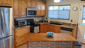 A kitchen with wooden cabinets, stainless steel appliances, a microwave, a stove, and a sink. - An oasis featuring a pool, where quiet luxury meets backyard tranquility. (Peoria)