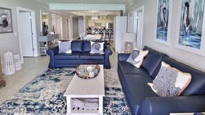 Ein geräumiges Wohnzimmer mit zwei dunkelblauen Sofas, einem weißen Couchtisch und einem gemusterten Teppich.