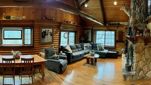 L’intérieur d’une cabane en rondins comprend un coin repas, un canapé et une cheminée.