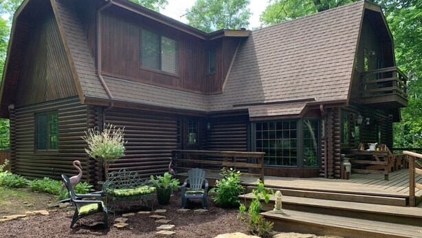 Une cabane en rondins dotée d’une terrasse et d’un espace salon extérieur.