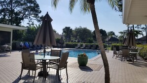 Un espace aménagé au bord de la piscine, avec des chaises longues, une table et des parasols.