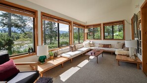 Un salón espacioso con ventanas amplias, un conjunto de sofás, una mesa de centro y una chimenea.