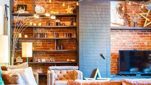 A cozy living room with a brick wall, a fireplace, a television, and a bookshelf filled with books and decorative items. - Historic Loft in Heart of St Elmo ★ Staycation Gem (Chattanooga)