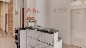 A reception area with a marble counter, a flower arrangement, and a sign that reads "YOYO". - OYO 3170 Songo Residence (Semarang)