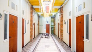 A hallway with wooden doors, numbered 102 and 112, leading to rooms. - OYO 3170 Songo Residence (Semarang)
