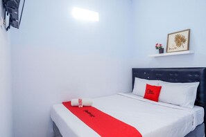 A neatly made bed with white and red bedding, a red pillow, and a red towel on a white bedspread. - OYO 3170 Songo Residence (Semarang)