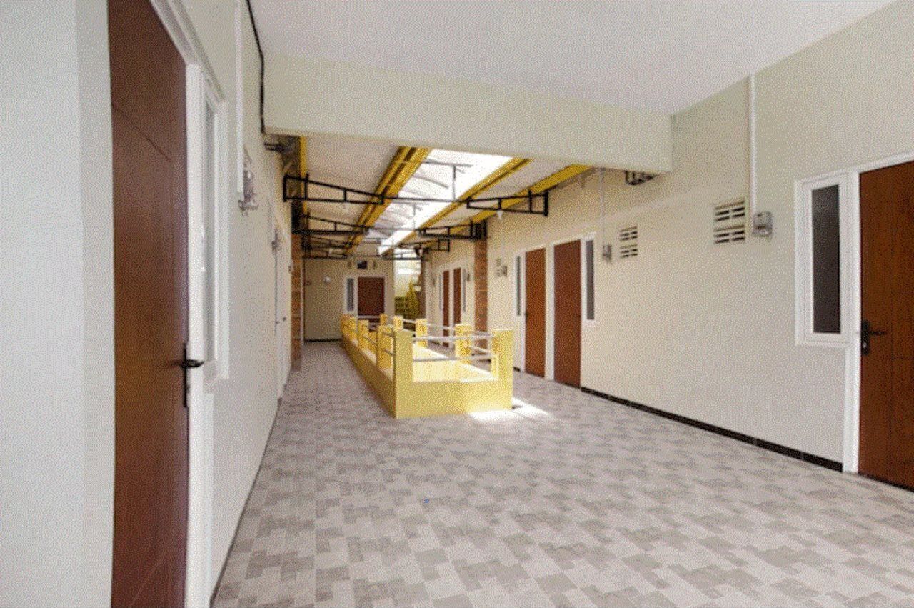 A corridor with lockers, a yellow barrier, and doors leading to rooms.