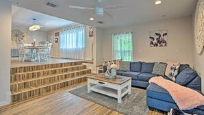 Un salón amplio con un sofá gris, una mesa de centro y una escalera que lleva a un piso superior.