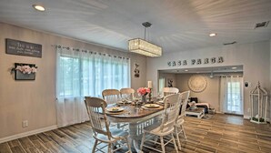 Comedor con una mesa de madera dispuesta para cuatro personas, rodeado de sillas blancas.