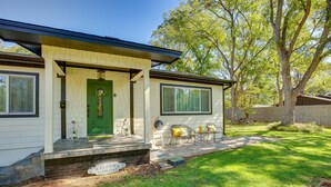 Una casa con puerta verde, un letrero de bienvenida y un patio con mobiliario exterior.