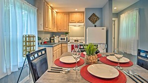 A dining area with a wooden table set for four, surrounded by chairs.