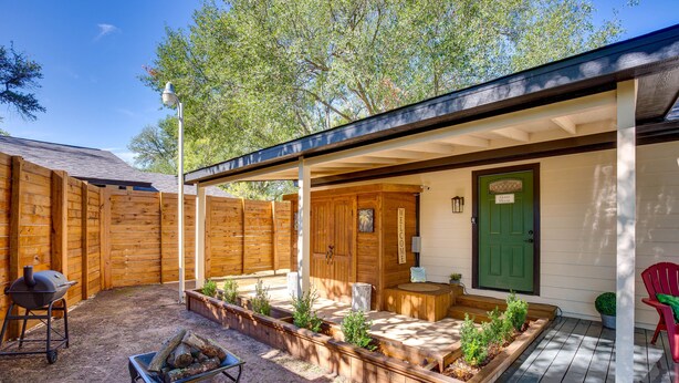 A covered patio with wooden deck, a barbecue grill, and a fire pit.