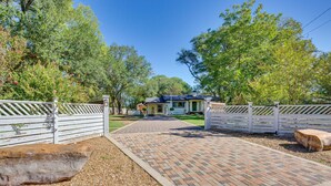 A gated entrance with a paved pathway leading to a house with a blue roof.