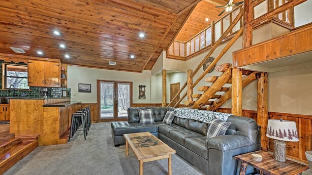 A spacious living area with a leather sofa, wooden coffee table, and a staircase with wooden railings. - 2 Decks & Game Room: Expansive Family Cabin (Pinetop-Lakeside)
