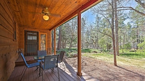 A wooden cabin with a covered porch, a table with chairs, and a view of a forest. - 2 Decks & Game Room: Expansive Family Cabin (Pinetop-Lakeside)