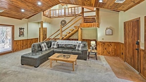 A spacious living room with a large sectional sofa, a wooden coffee table, and a staircase leading to an upper level. - 2 Decks & Game Room: Expansive Family Cabin (Pinetop-Lakeside)