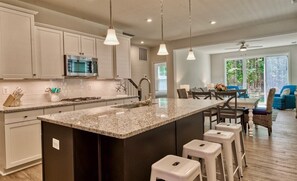 A modern kitchen with granite countertops, stainless steel appliances, and pendant lighting.