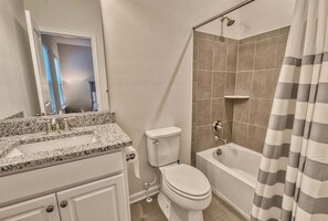 Une salle de bain équipée d’un lavabo, de toilettes, d’une baignoire et d’un rideau de douche.