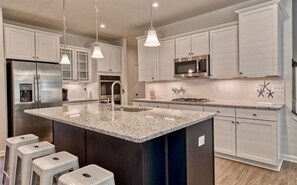 A modern kitchen with a central island, stainless steel appliances, and white cabinetry.