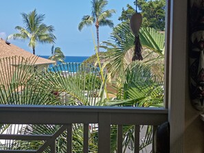 Vista di un resort sulla spiaggia, con palme, una piscina e un cielo azzurro limpido.