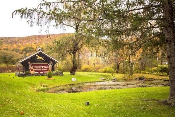 A mountain resort with a prominent sign, a small pond, and surrounding greenery.