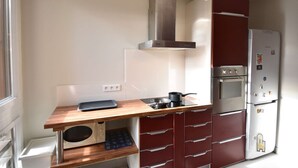 A compact kitchen with a wooden countertop, a built-in oven, a stainless steel range hood, and a refrigerator. - Seignosse “LE PIGNADA” Apartment for 4 people. (SEIGNOSSE)