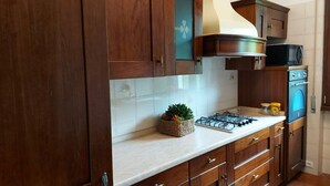 A kitchen with wooden cabinets, a gas stove, a microwave, and a sink.