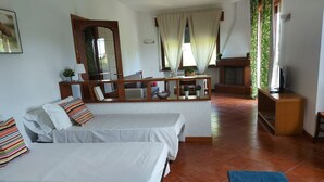 A room with two beds, a sofa, a small table, a mirror, and a window with curtains.