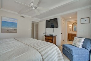 Quarto com uma cama, televisão, cômoda e uma cadeira.