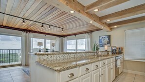 Een keuken met een groot eiland, witte kasten en uitzicht op de omgeving.