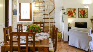 A dining area with a wooden table, chairs, and a spiral staircase leading to an upper level.