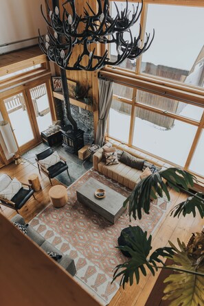 A cozy living room with a fireplace, comfortable seating, and large windows.