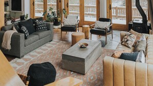 Een ruime woonkamer met hoge plafonds, houten balken en grote ramen.