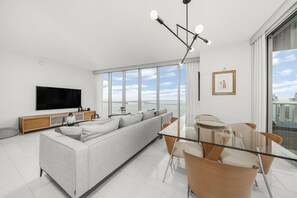 Relax in this stylish living room with a large sofa, dining table, and flat-screen TV.