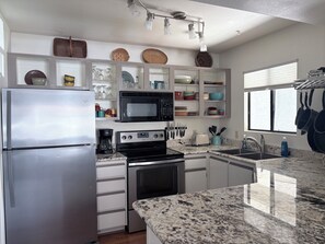 A modern kitchen with a stainless steel refrigerator, a microwave, a stove, and a sink. - Recently remodeled  !, two pools, gym & near hiking,easy walk to restaurants (Tucson)