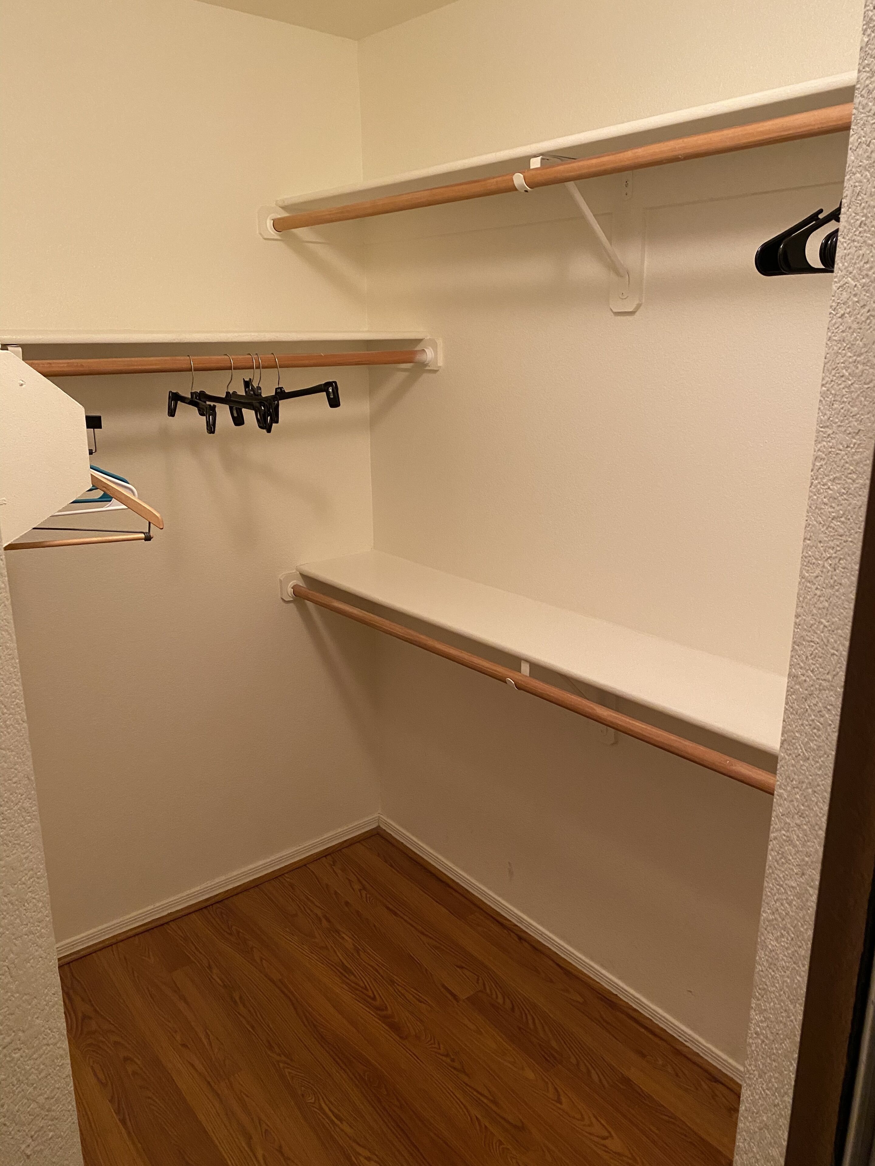 Ein Eckschrank mit Holzböden und Kleiderstange.