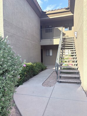 Un immeuble résidentiel avec un chemin en béton menant à un escalier en bois.