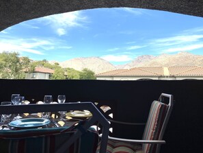 Un comedor con una mesa dispuesta para dos personas, con vistas a un paisaje montañoso.